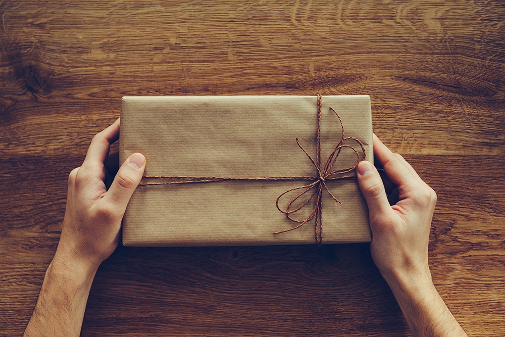 Close-up top view of man holding gift box over the rustic wooden grain
